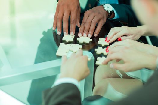 closeup.business team assembling puzzle pieces on your desktop .concept business solutions
