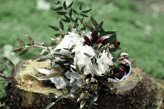 close up.flower arrangement on a stump on the grass background.