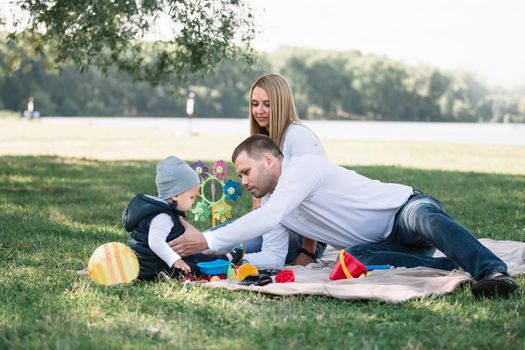 happy family sitting on the grass in the Park on a spring day