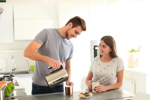 Cute young couple drinking coffee in kitchen