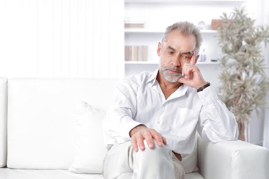 dreamy adult businessman sitting on sofa in office.