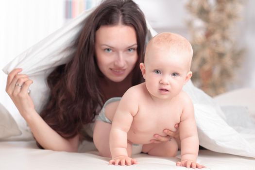 happy mother plays with the baby lying on the bed . the concept of education