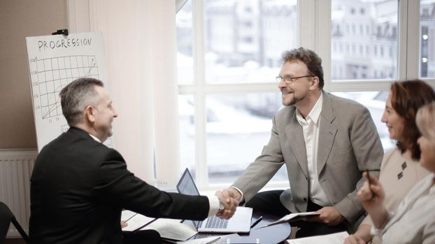 business partners shaking hands before business meeting in office