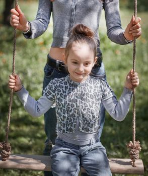 mom swings her pretty daughter on the swing . the concept of active recreation