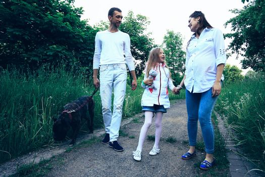 pretty daughter with her parents and pet dog in the Park in summer Sunny day.