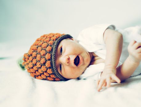 cute newborn baby in knitted hat lying on the bed