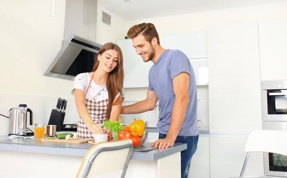 Portrait of happy young couple cooking together in the kitchen at home.