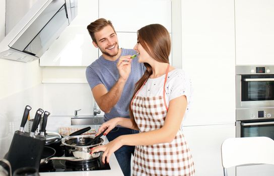 Portrait of happy young couple cooking together in the kitchen at home.