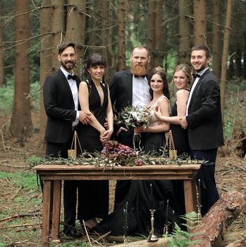 guests and a couple of newlyweds near the picnic table in the woods.
