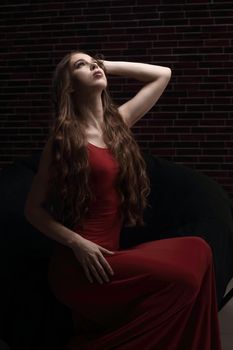 stylish young woman in red dress sitting in a chair.