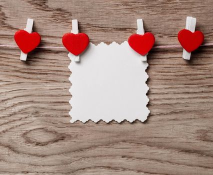 hearts and blank note on the clothespin on wooden background. photo with copy space