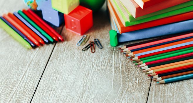 School supplies lying on the wooden floor. Along with books, dice, pencils, and markers form the school song