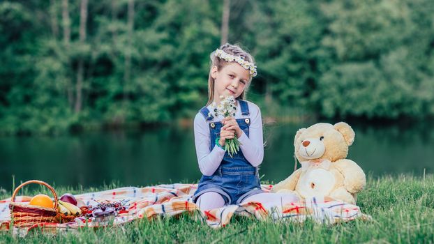 little girl with a bouquet of daisies sitting on the lawn on a summer day.