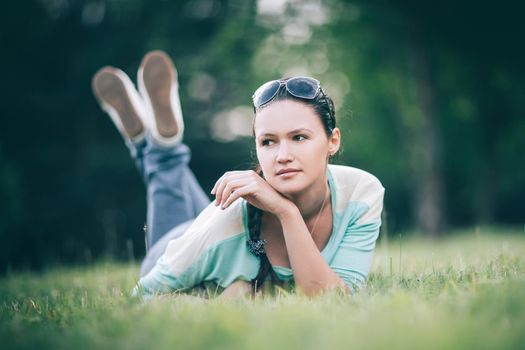 attractive young woman lying on the grass on a summer day. photo on blurred background