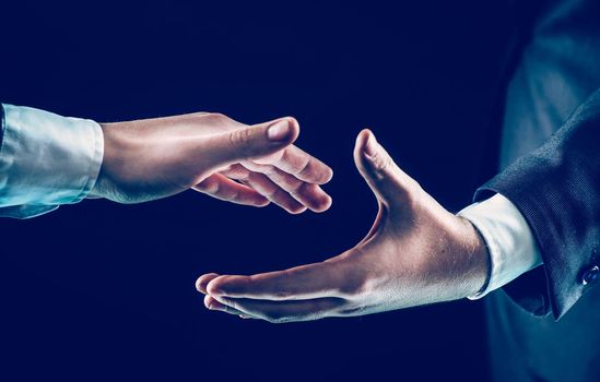 closeup of two businessmen stretches his hand forward for a handshake.photo on a black background and has space for your text.