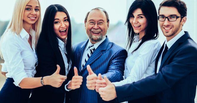 successful friendly business team on office background all showing thumbs up