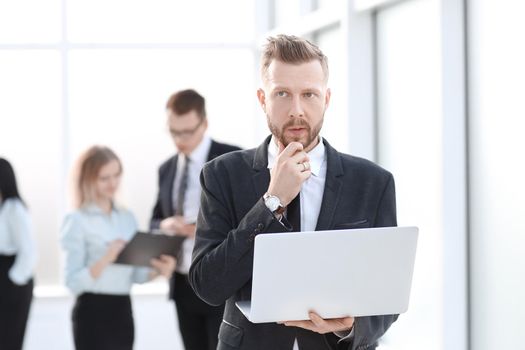 businessman with laptop on the background of the office lobby. people and technology