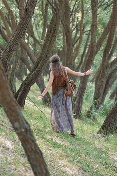 rear view.young hippie woman standing among the trees in the forest . the concept of unity with nature