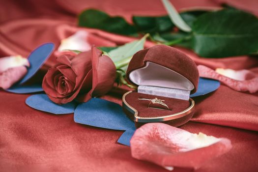 diamond ring and rose on bright red background. photo with copy space