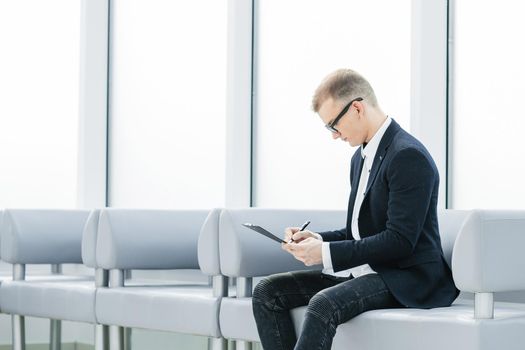 businessman reading a business document sitting in the office lobby. photo with copy space