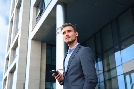Young urban businessman professional on smartphone walking in street using mobile phone.