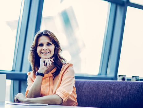 business woman sitting behind a Desk in the spacious office. the photo has a empty space for your text