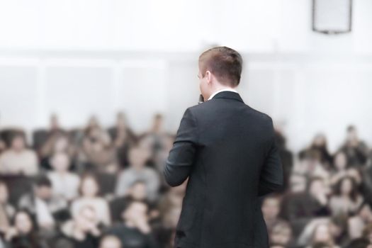 rear view.young businessman at a business conference with a public report. Entrepreneurship club.