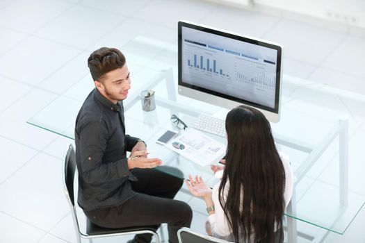 two employees discuss financial data sitting at an office Desk. office weekdays