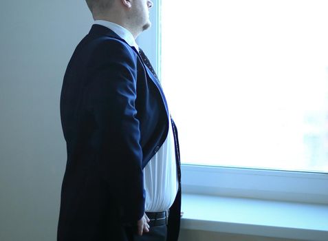 serious confident businessman looks out the window of the office . photo with copy space
