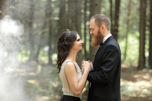 bride and groom standing in the woods.photo with cloud effect.