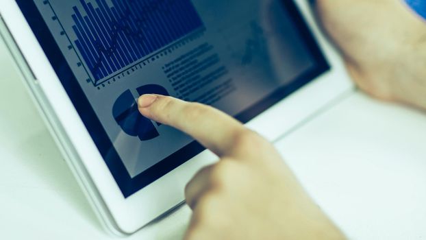 closeup of businessman using digital tablet, working with the financial schedule at the Desk .the photo has a empty space for your text