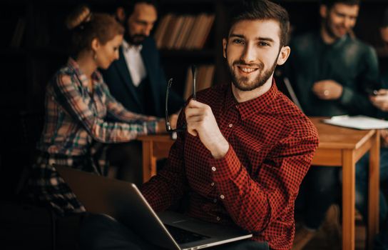 in the foreground the successful employee of the company with laptop on the background of business team