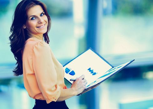attractive modern young business woman with a folder in his hand the office