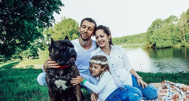 ,little daughter and their dog on a picnic by the river.the photo has a space for your text