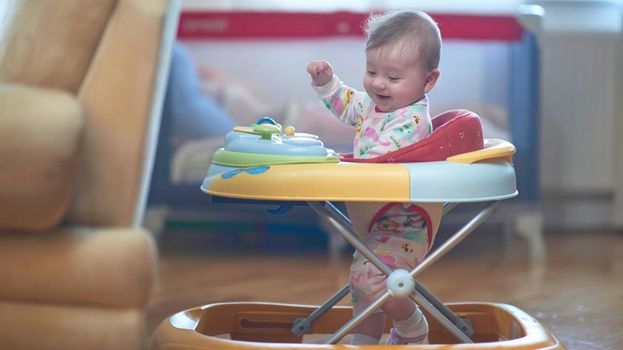 cute little baby learning to walk in walker at home