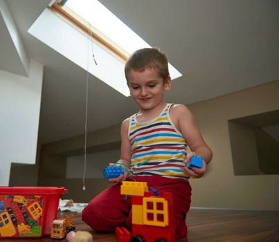 Little boy child playing with creative plastic toys indoor, building different cars and building  objects