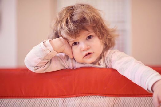 little baby girl with strange hairstyle and curlers in bed at home