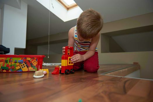 Little boy child playing with creative plastic toys indoor, building different cars and building  objects