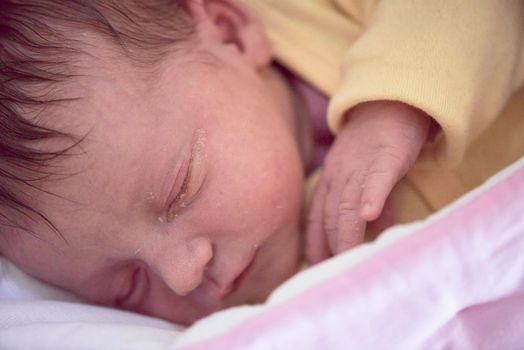 newborn baby child sleeping in plastic bed at hospital  wearing blanket coat