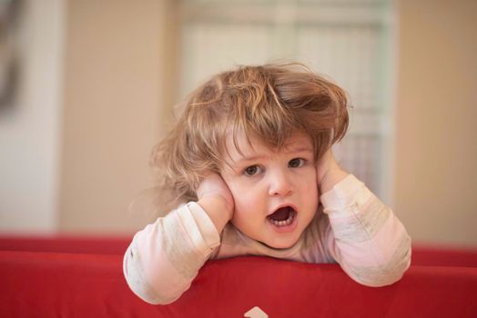 little baby girl with strange hairstyle and curlers in bed at home