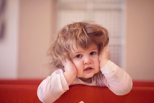 little baby girl with strange hairstyle and curlers in bed at home