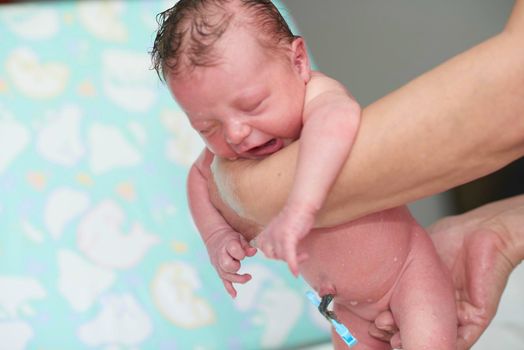 Grandmother is bathing Newborn baby girl  at home holding in towel