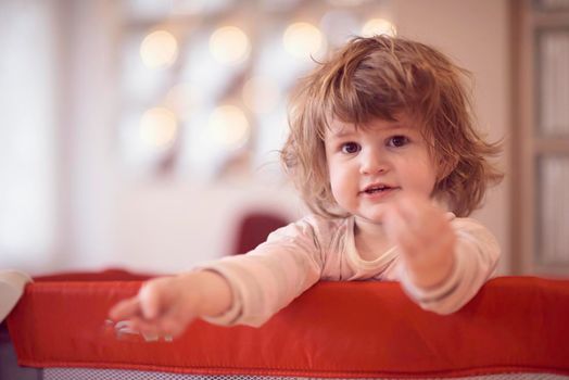 little baby girl with strange hairstyle and curlers in bed at home