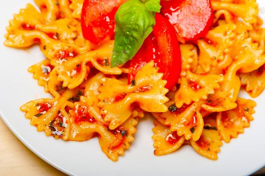 Italian pasta farfalle butterfly bow-tie with tomato basil sauce over white rustic wood table