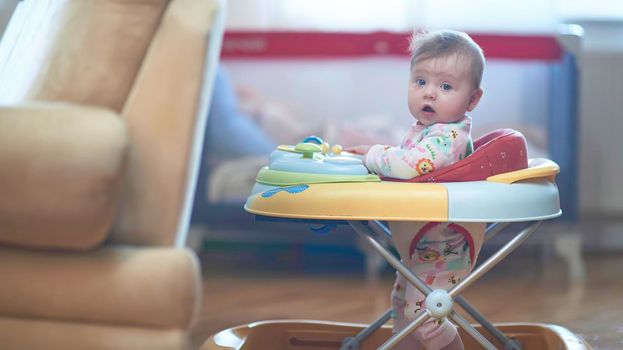 cute little baby learning to walk in walker at home