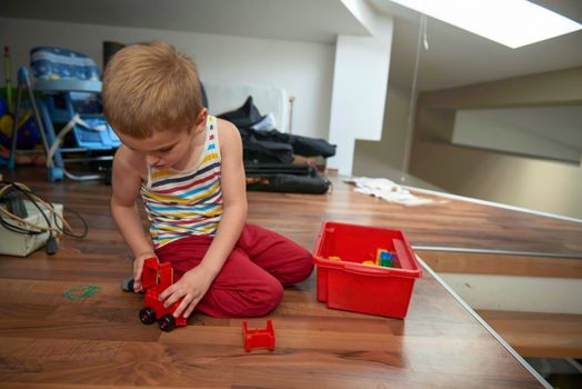 Little boy child playing with creative plastic toys indoor, building different cars and building  objects