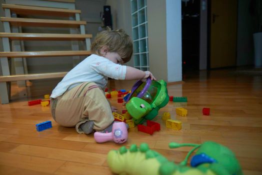 Adorable cute beautiful little baby girl playing with toys at home. Happy healthy child having fun with toy Kid learning different skills