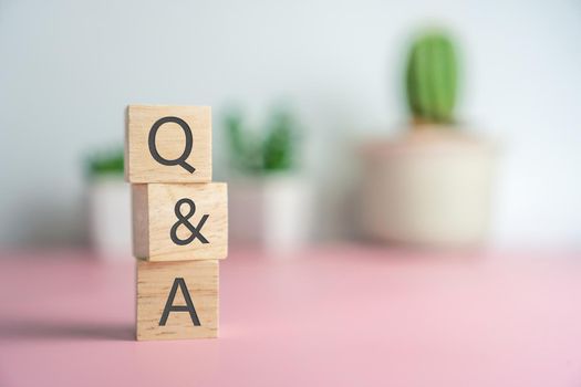 Q and A alphabet on wooden cube in hand hold with background. Question and answer meaning concept.