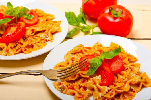 Italian pasta farfalle butterfly bow-tie with tomato basil sauce over white rustic wood table