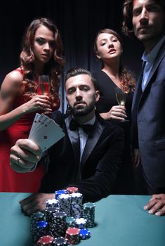 Young handsome man sitting behind poker table with card